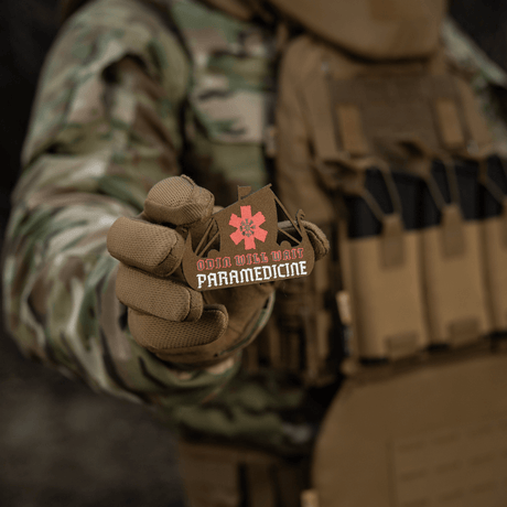 M-Tac Patch Viking Evac i soldatens hånd, viser Odin will wait paramedicine motiv. Camouflage jakke og taktisk vest baggrund.