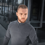 Mand iført M-Tac Delta Polartec Fleecejakke, en stilren og funktionel jakke i grå med halv lynlås, ideel til kolde dage.