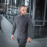 Mand iført M-Tac Delta Polartec Fleecejakke i grå med moderne baggrund, ideel til kolde dage med fremragende isoleringsmuligheder.