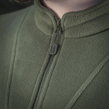 Nærbillede af M-Tac Delta Polartec Fleecejakke i grøn farve, der viser detail af lynlås og stofstruktur, fremstillet af Polartec® Micro Series-fleece.
