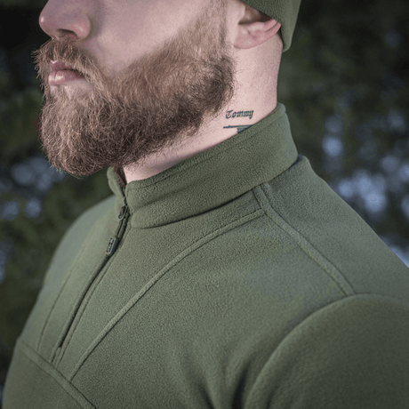 Mand iført M-Tac Delta Polartec Fleecejakke i grøn med tatovering på halsen, siddeprofilvisning i udendørs miljø.