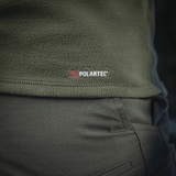 Nærbillede af M-Tac Delta Polartec Fleecejakke i olivengrøn med Polartec-logo, fremstillet af slidstærkt og åndbart Polartec® Micro Series-fleece.