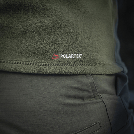 Nærbillede af M-Tac Delta Polartec Fleecejakke i olivengrøn med Polartec-logo, fremstillet af slidstærkt og åndbart Polartec® Micro Series-fleece.