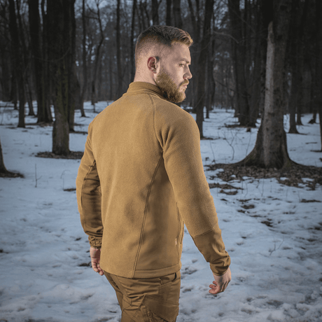M-Tac Polartec Sport Fleecejakke i en sneklædt skov, perfekt som yderlag eller mellemlag for varme og komfort.