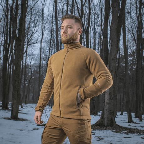 Mand iført M-Tac Polartec Sport Fleecejakke i en skov om vinteren