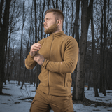 Mand iført M-Tac Polartec Sport Fleecejakke, står i skov med sne, demonstrerer jakken's komfort og funktionalitet i koldt vejr.