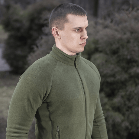 M-Tac Polartec Sport Fleecejakke i en grøn nuance, ideel til både overgangsperioder og som mellemlag i koldt vejr, bæres udendørs.
