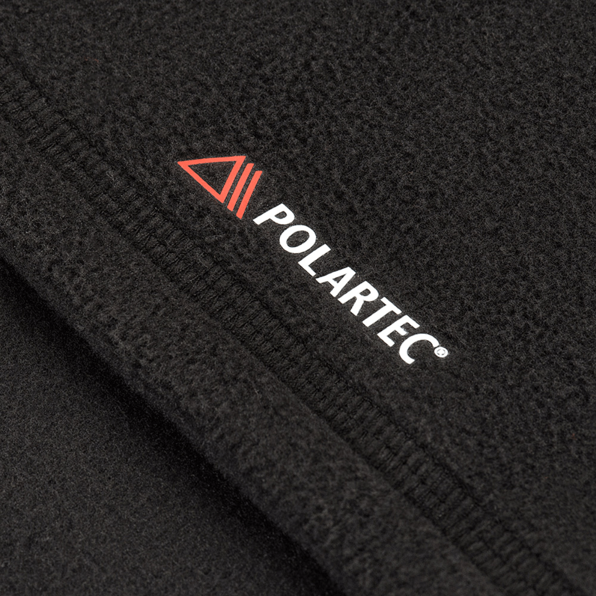 Nærbillede af sort fleece stof fra Polartec® med synlig syning og logo, brugt i M-Tac Delta Polartec Raglan Jakke.
