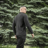 Mand iført M-Tac Delta Polartec Raglan Jakke, sort farve, med behagelig og varm fleece, ideel til udendørs brug.