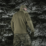 Mand iført M-Tac Battle Fleece Polartec Jakke i sneklædt skov, set bagfra med anatomisk pasform og camouflagebukser.