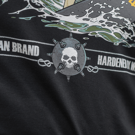 Close-up af M-Tac T-Shirt Surf Club med grafik af dødningehoved, bølger og tekst, inspireret af specialoperationer og surfscener.