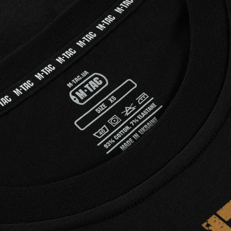 Nærbillede af M-Tac T-Shirt etiket, viser størrelse XS, 93% bomuld og 7% elastan, lavet i Ukraine.
