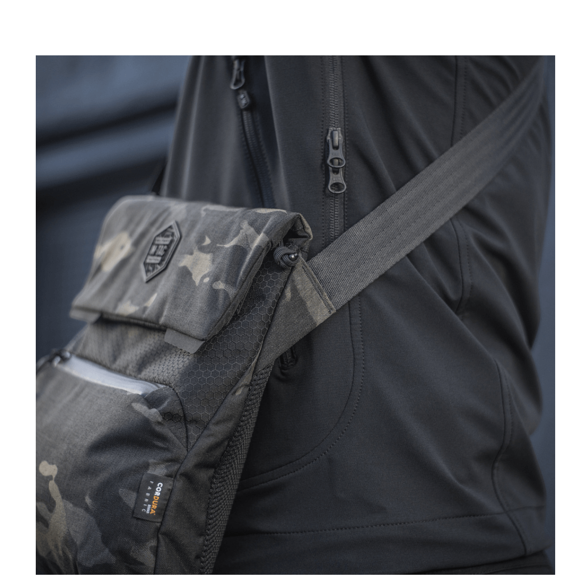 M-Tac Konvert Taske Elite i camouflage, robust design med Cordura stof, bærer en praktisk magnetventillukning og justerbar skulderrem.