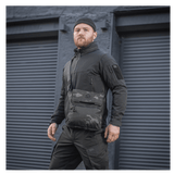 Mand iført M-Tac Konvert Taske Elite i sort Camouflage-stil foran industrielle garagedøre