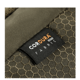 Nærbillede af M-Tac Konvert Taske Elite med Cordura-materiale label, der viser slidstærkt stof. Taskens brune farve og mønster er synlige.