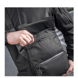 Mand med M-Tac Konvert Taske Elite, lavet af holdbar Cordura, med magnetlukning og justerbar skulderrem.