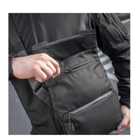 Mand med M-Tac Konvert Taske Elite, lavet af holdbar Cordura, med magnetlukning og justerbar skulderrem.