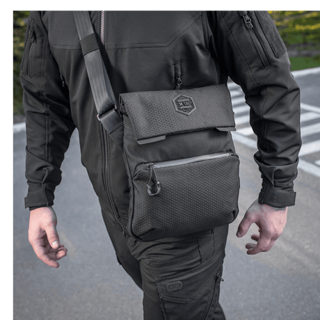 Mand bærer M-Tac Konvert Taske Elite i sort med justerbar skulderrem, fremstillet af slidstærk Cordura 500D og Cordura Hex 1000D.