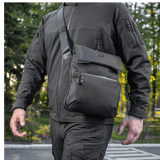 Mand bærer M-Tac Konvert Taske Elite i Cordura materiale, justerbar skulderrem og tablet-design, set udefra i et udendørs miljø.