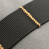 M-Tac Urban Line City Patrol Taske materiale close-up af sort skulderbånd med orange syninger, 600D polyester, vandafvisende egenskaber.