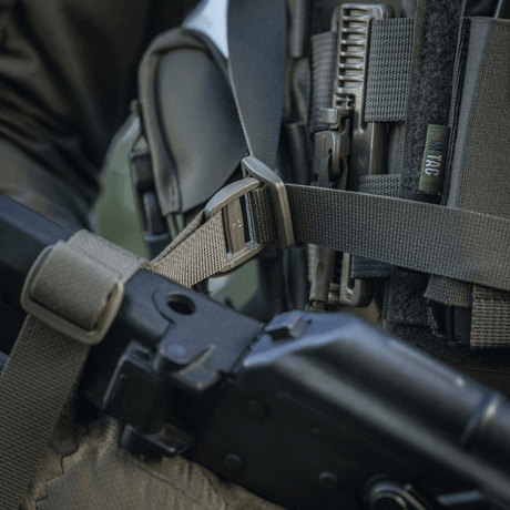 M-Tac Våbenbælte med Tre Punkter i brug til patruljering og konvojopgaver, designet til let våbenoverførsel mellem skuldre.