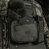 M-Tac organizer pouch Elite fastgjort til taktisk vest med M.O.L.L.E.-system, holder nødudstyr og værktøjer, åben ved 90 grader.
