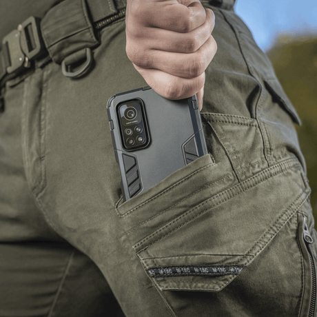 Nærbillede af M-Tac Bukser Aggressor Gen.II Vintage med mobiltelefon i lommen, viser praktisk og stilfuldt design til hverdag og marken.