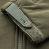 Nærbillede af en M-Tac Soft Shell Police Jakke i beige, der viser lynlås og velcrolukning på ærmet.