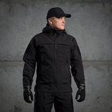 Mand iført M-Tac Soft Shell Police Jakke, sort jakke med justerbare elementer og indvendig fleece, designet til beskyttelse mod vind og vejr.