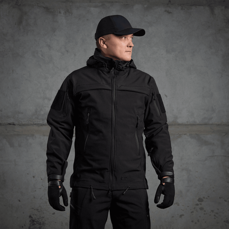 Mand iført M-Tac Soft Shell Police Jakke, sort jakke med justerbare elementer og indvendig fleece, designet til beskyttelse mod vind og vejr.