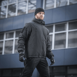 Mand iført M-Tac Alpha Gen.III Pro Vinterjakke i bymiljø, optimal til ekstreme forhold med komfort og vandafvisende materiale.