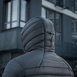 Person iført M-Tac Stalker Gen. III Primaloft Jakke med hætte op foran en moderne bygning