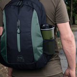 Mand med rygsæk, der indeholder en M-Tac Termokop 450 ml med Ventil, ideel til varme og kolde drikke på farten.