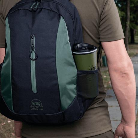 Mand med rygsæk, der indeholder en M-Tac Termokop 450 ml med Ventil, ideel til varme og kolde drikke på farten.
