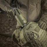 M-Tac Termoflaske 750 ml med Folde-ske til camping i skovmijø, robust design, god til varme drikke, ideel til udendørs brug og eventyr.