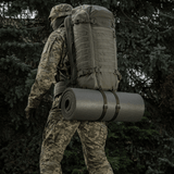 Soldat med rygsæk og M-Tac Liggeunderlag 20 mm (60x180 cm) i naturen til friluftsliv og ekstremt klima.