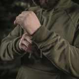 Person iført M-Tac Cotton Raglan Hard Hoodie i 100% bomuld med fleecefor i grøn, viser elastisk manchet på ærmet, perfekt til de køligere årstider.