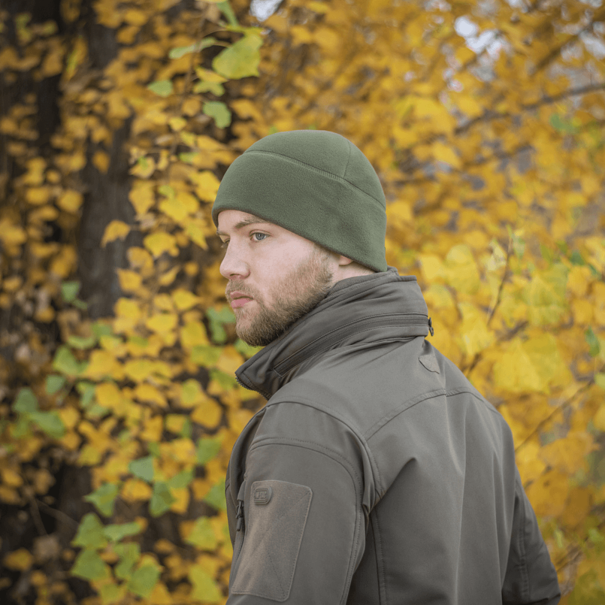 Mand iført M-Tac Fleece Polartec Watch Cap i skov med efterårsblade