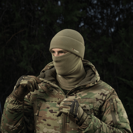 Person iført M-Tac Fleece Polartec Watch Cap i koldt udendørs miljø, perfekt til vinteraktiviteter med kamuflagejakke.
