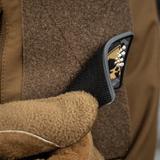 Brun handske fastgør M-Tac Patch Joker Skull 3D PVC på jakke med velcro.