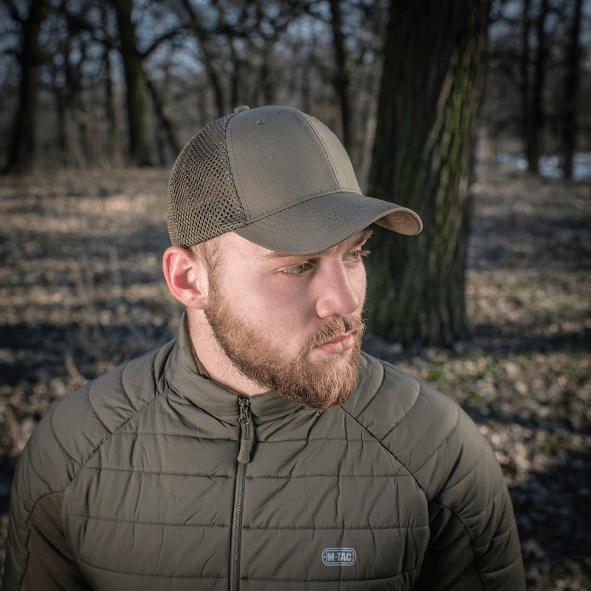 M-Tac Mesh Flex Ripstop Baseball Cap bæres udendørs i en skov, viser holdbarhed og god ventilation med ripstop og mesh design