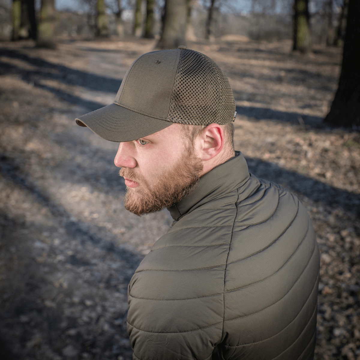 Mand iført M-Tac Mesh Flex Ripstop Baseball Cap i skov, viser holdbarhed og ventilation i udendørs omgivelser