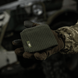 M-Tac Rip-Stop Fleece Hjelmliner vises i en hånd iført taktik handsker i et udendørs militært miljø, kompakt og klar til brug.