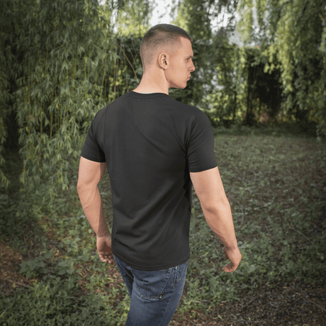 Mand iført en M-Tac Raglan T-Shirt 93/7 med komfortable raglanærmer i en naturlig udendørs omgivelser.