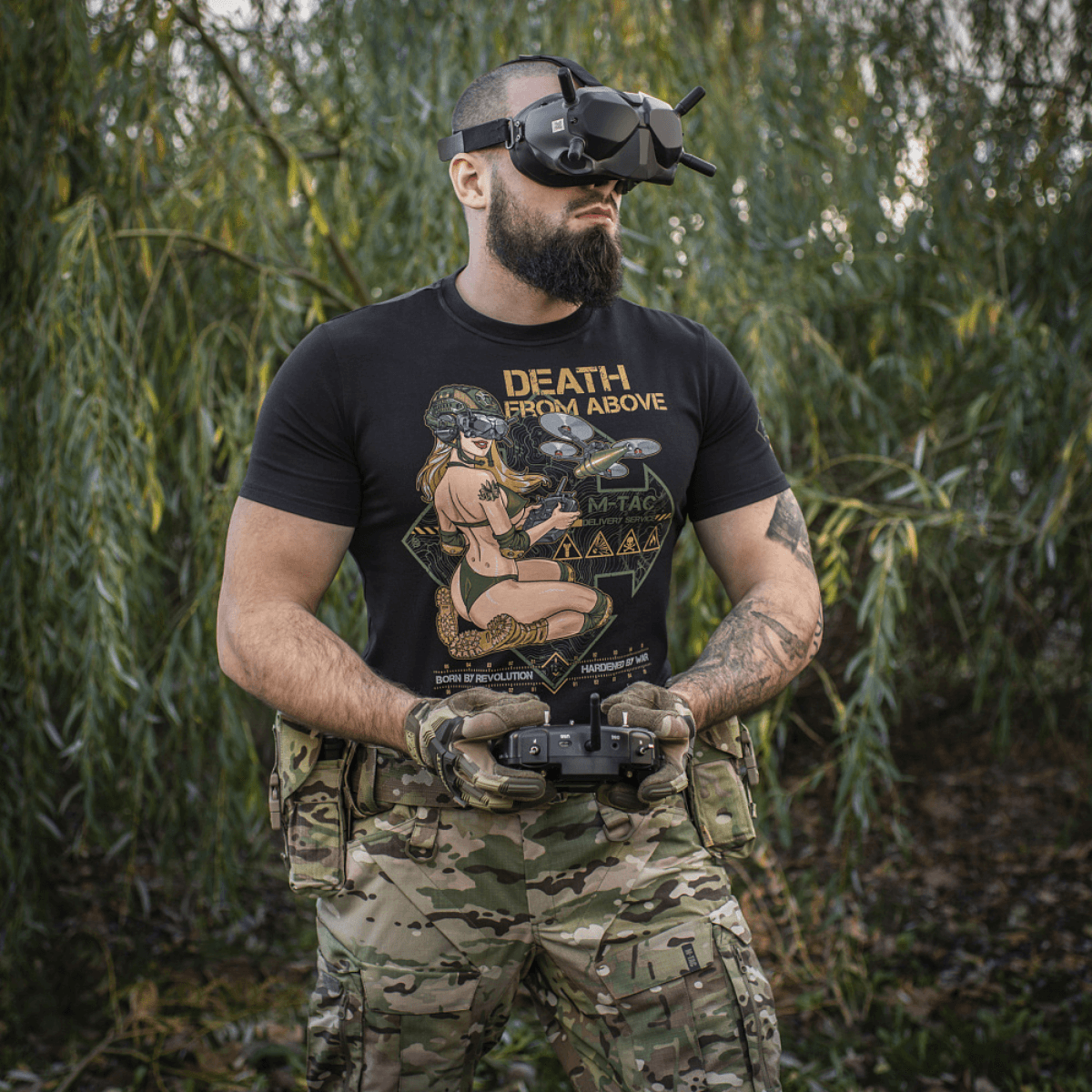 Mand iført M-Tac T-Shirt Delivery Service med Pin-Up print og dronebriller, sort skjorte med "Death from Above" tekst i skovmiljø.