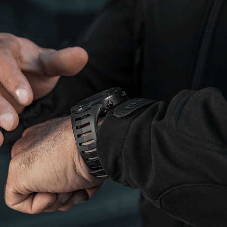 Person justerer M-Tac Tactical Ur 2147 på håndled. Ideel til outdoor og taktisk brug med robust design og praktiske funktioner.