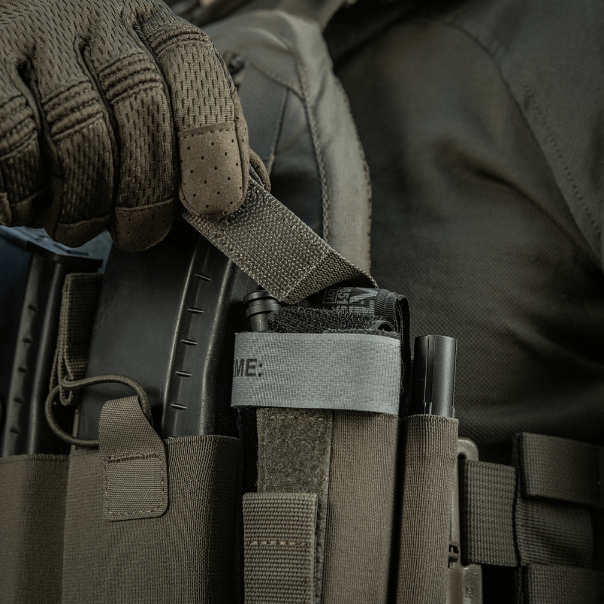 M‑Tac Tourniquet Pouch Elastic Gen.5 monteret på taktisk udstyr, viser hurtig adgang til tourniquet med elastisk velcrobånd.