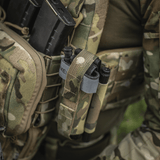 Taktisk gear med M‑Tac Tourniquet Pouch Elastic Gen.5, fastgjort til uniform med CAT tourniquet, camouflagemønster.