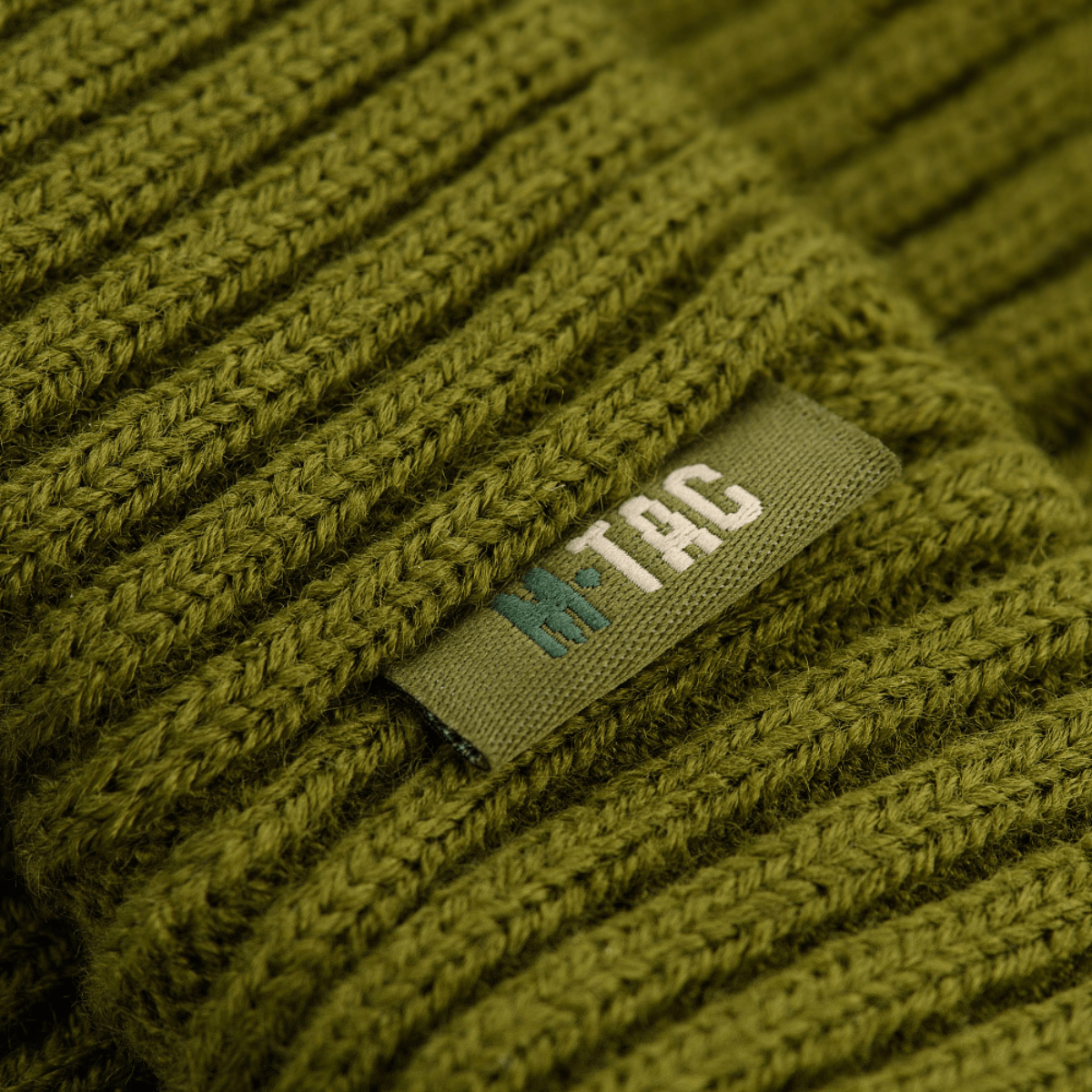 M-Tac Watch Cap 100% Akryl i olivengrøn industriel strik, vist med mærket for holdbar, varm hue i køligt vejr.