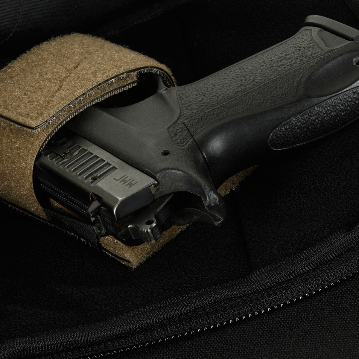 Nærbillede af en pistol i en M-Tac Sphaera Hardsling Bag Large Elite med Velcro, lavet af robust Cordura stof med velcro fastgørelse.